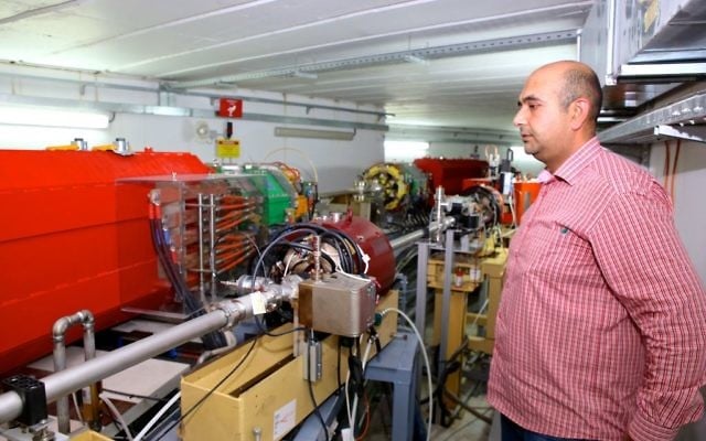 An employee from SESAME stands next to the particle accelerator in Allan, Jordan. (Sharing Knowledge Foundation)