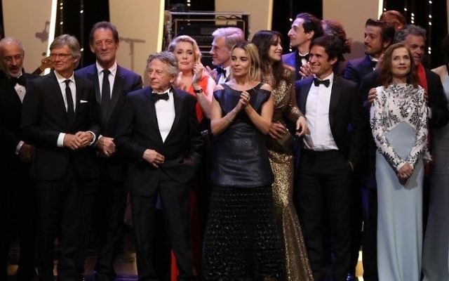 Israeli director Amos Gitai (far right, wearing a red scarf) stands on stage with a pantheon of screen stars on May 23, 2017 during the '70th Anniversary' ceremony of the Cannes Film Festival in Cannes, southern France. / AFP PHOTO / Valery HACHE