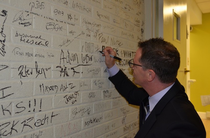 Joshua Malina signs his name on the wall of Sixth and I, a historic Washington, DC, synagogue, at a Shavuot event last year. The synagogue's Shavuot event this year features Jeffrey Goldberg, editor of the Atlantic, and Imam Abdullah Antepli. (Courtesy of Sixth and I/via JTA) Joshua Malina signs his name on the wall of Sixth and I, a historic Washington, DC, synagogue, at a Shavuot event last year. The synagogue's Shavuot event this year features Jeffrey Goldberg, editor of the Atlantic, and Imam Abdullah Antepli. (Courtesy of Sixth and I/via JTA)