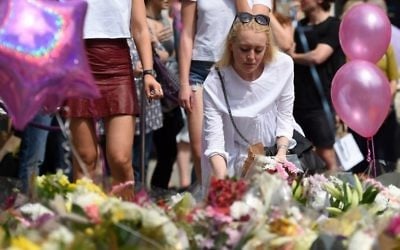 A woman places flowers in St Ann's Square in Manchester, northwest England on May 25, 2017, in tribute to the victims of the May 22 terror attack at the Manchester Arena. / AFP PHOTO / Oli SCARFF