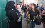 During a peace walk organized by Tag Meir a woman hands flowers to Arab shopkeepers in Jerusalem's Old City ahead of the Jerusalem Day flag parade, May 24, 2017. (Courtesy)