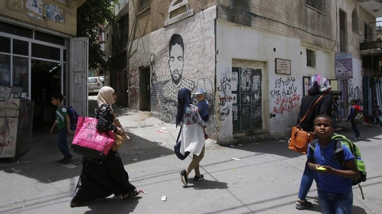 Palestinians walk past graffiti in Deheishe Refugee Camp near the West Bank town of Bethlehem on May 14, 2017. (AFP Photo/Musa Al Shaer) Palestinians walk past graffiti in Deheishe Refugee Camp near the West Bank town of Bethlehem on May 14, 2017. (AFP Photo/Musa Al Shaer)