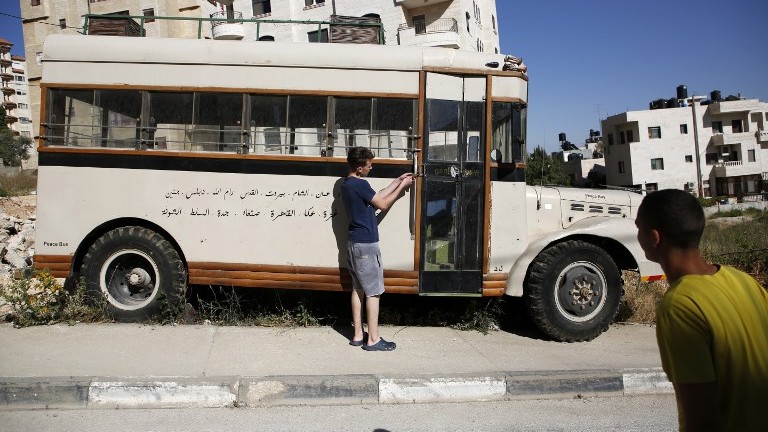 Mohammed Nassar opens the door of a restored pre-1967 bus which bears writing in Arabic of the names of the cities it used to visit, parked on the side of a street in the West Bank city of Ramallah on May 31, 2017. (AFP Photo/Abbas Momani) Mohammed Nassar opens the door of a restored pre-1967 bus which bears writing in Arabic of the names of the cities it used to visit, parked on the side of a street in the West Bank city of Ramallah on May 31, 2017. (AFP Photo/Abbas Momani)
