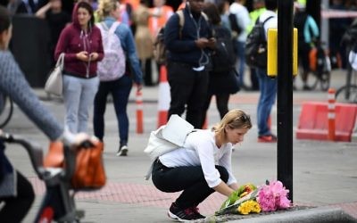 A woman lays a bouquet of flowers at a pedestrian crossing by Borough market in London on June 5, 2017. (AFP PHOTO / Justin TALLIS)