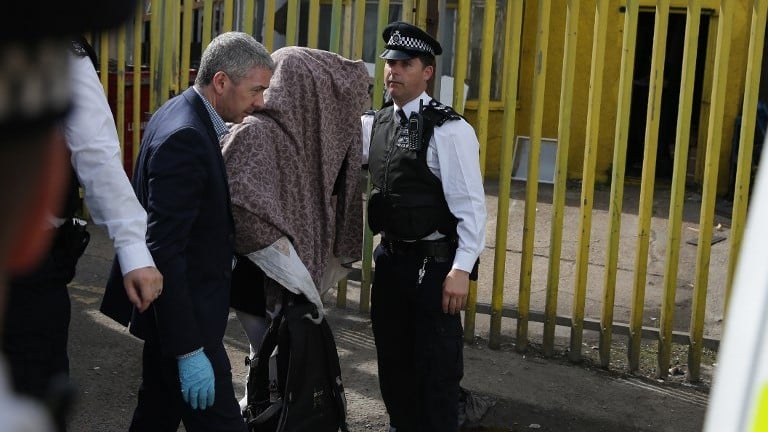 Police officers escort a person, with their head covered, to a police van, in Barking, East London on June 5, 2017, following a dawn raid on a property as part of the investigation into the June 3 terror attack in central London. (AFP Photo/Daniel Leal-Olivas)