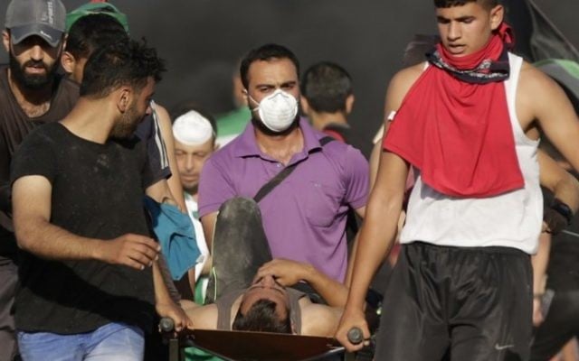 Palestinian protesters carry a wounded man during clashes with Israeli security forces near the border fence east of Jabalia refugee camp on June 5, 2017 AFP /FP/MAHMUD HAMS)