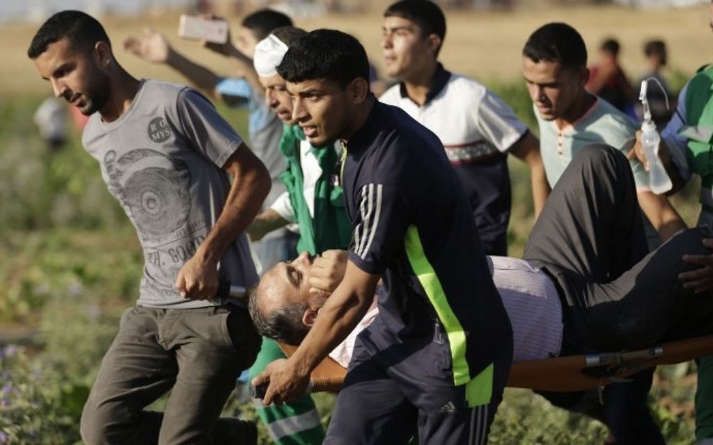 Palestinians carry a wounded man during clashes with IDF following a demonstration near the border fence east of Jabalia refugee camp on June 5, 2017. (AFP Photo/FP/Mahmud Hams)