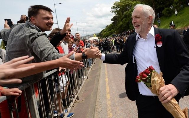 Britain's main opposition Labour Party leader Jeremy Corbyn greets supporters as he leaves after attending a campaign visit in Colwyn Bay, north Wales on June 7, 2017, on the eve of the general election. (AFP PHOTO / Oli SCARFF)