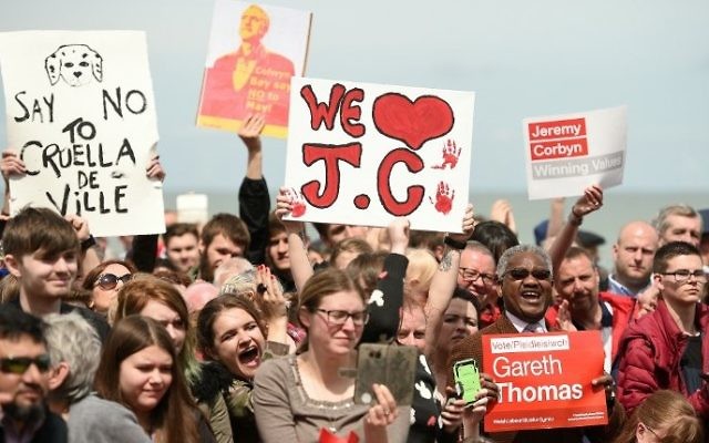 Supporters of Britain's main opposition Labour Party hold placards as the leader Jeremy Corbyn speaks during a campaign visit in Colwyn Bay, north Wales on June 7, 2017, on the eve of the general election. (AFP PHOTO / Oli SCARFF)