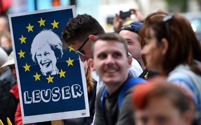 A demonstrator holds a placard depicting an image of Britain's Prime Minister Theresa May, surrounded by the stars of the EU flag and with the words 'Leuser,' as he stands outside the entrance to Downing Street, in central London on June 9, 2017, following the result of the general election. (AFP/Glyn Kirk)