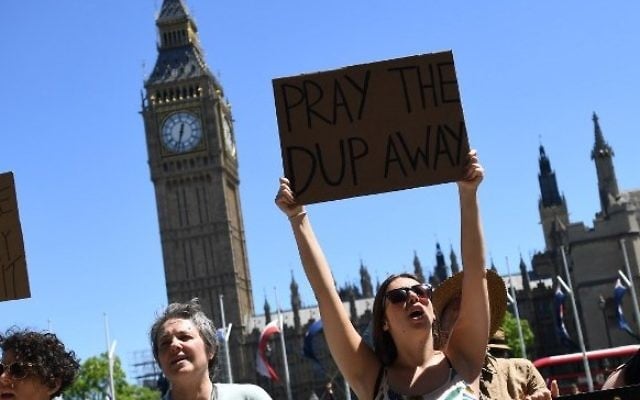 Protesters hold up placards as they protest in Parliament Square in front of the Houses of Parliament in central London on June 10, 2017 against the Democratic Unionist Party (AFP PHOTO / Justin TALLIS)