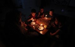A Palestinian family eats dinner by candlelight at their makeshift home in the Rafah refugee camp, in the southern Gaza Strip, during a power outage June 11, 2017. (AFP/Said Khatib)