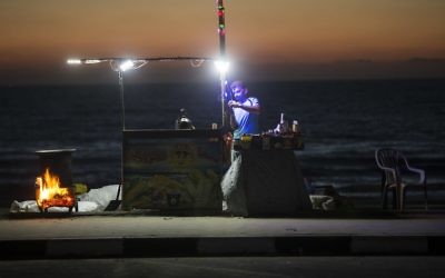 A Palestinian street vendor stands behind his stall in front of the beach in Gaza City during a power outage on June 11, 2017. (AFP/Mahmud Hams)