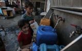 Palestinian children fill jerrycans with drinking water from public taps in the southern Gaza Strip, June 11, 2017. (AFP/SAID KHATIB)