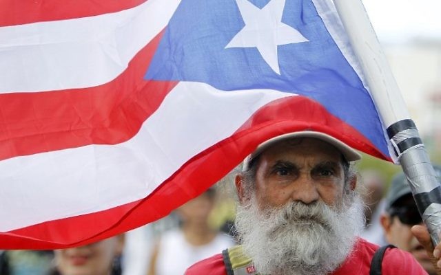 A man carries a Puerto Rican flag during a protest against the referendum for Puerto Rico political status in San Juan, on June 11, 2017. (AFP PHOTO / Ricardo ARDUENGO) A man carries a Puerto Rican flag during a protest against the referendum for Puerto Rico political status in San Juan, on June 11, 2017. (AFP PHOTO / Ricardo ARDUENGO)