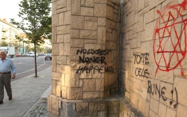 A man walk past the wall of a Synagogue with 'Holocaust never happened' and "All the best!' written on it in Cluj-Napoca, Romania, June 12, 2017 (AFP PHOTO / MIRCEA ROSCA)