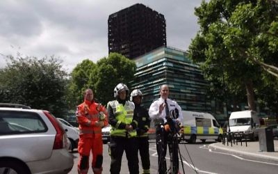London Police Commander Stuart Cundy (R), joined by firemen and an emergency worker, makes a statement to the media against the backdrop of the remains of Grenfell Tower, a residential tower block in west London which was gutted by fire, in west London on June 16, 2017. (Daniel LEAL-OLIVAS / AFP)