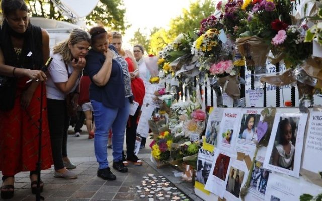 People look at posters of missing persons attached to railings after the fire that gutted Grenfell Tower, a residential tower block in west London on June 14. (AFP PHOTO / Tolga AKMEN) 