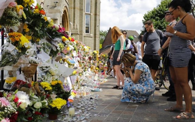 People look at floral tributes outside the Notting Hill Methodist Church, left for the victims of the June 14 Grenfell Tower block fire, in Kensington, west London, on June 17, 2017. (AFP PHOTO / Tolga AKMEN)