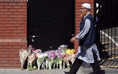 A man walks past floral tributes outside Finsbury Park Mosque in the Finsbury Park area of north London, on June 19, 2017, near to where a vehicle was driven into pedestrians. (Tolga AKMEN / AFP)