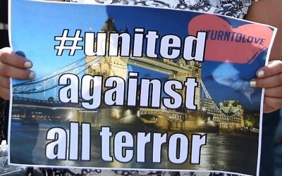 A woman holds a banner as she stands art a Police cordon close to the scene of a van attack in Finsbury Park, north London on June 19, 2017. (AFP/Isabel Infantes) 