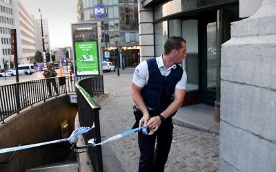 A police official is watched by a soldier as he uses tape to cordon off an area outside Gare Centrale in Brussels on June 20, 2017, after an explosion in the Belgian capital. (AFP PHOTO / Emmanuel DUNAND)