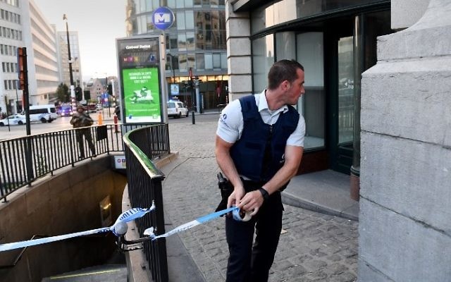 A police official is watched by a soldier as he uses tape to cordon off an area outside Gare Centrale in Brussels on June 20, 2017, after an explosion in the Belgian capital. (AFP PHOTO / Emmanuel DUNAND)