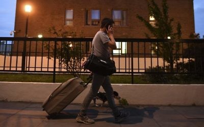 A resident talks on a cell phone as he leaves the Burnham Tower residential block on the Chalcots Estate in north London on June 23, 2017 after being evacuated because of fire safety concerns. ( AFP PHOTO / Justin TALLIS)