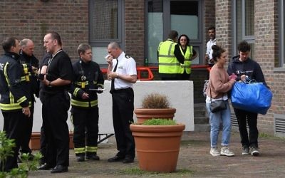 Residents (R) with belongings leave Burnham Tower residential block on the Chalcots Estate in north London on June 24, 2017 as residents evacuate because of fire safety concerns. ( AFP PHOTO / Justin TALLIS)