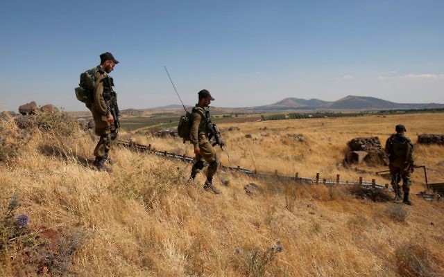 Illustrative: Israeli soldiers patrol near the border with Syria after projectiles fired from the war-torn country hit the Israeli Golan Heights on June 24, 2017. (AFP Photo/Jalaa Marey) Illustrative: Israeli soldiers patrol near the border with Syria after projectiles fired from the war-torn country hit the Israeli Golan Heights on June 24, 2017. (AFP Photo/Jalaa Marey)