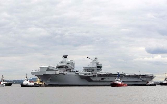 Tug boats maneuver the 65,000-ton British aircraft carrier HMS Queen Elizabeth on the Firth of Forth in east Scotland, on June 26, 2016, after escorting it out of its berth in Rosyth Naval dockyard to begin sea trials. (Andy Buchanan/AFP)