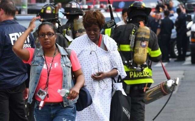 A patient walks past fire fighters at the Bronx-Lebanon Hospital as police respond to an active shooter north of Manhattan in New York on June 30, 2017.( AFP PHOTO / TIMOTHY A. CLARY)