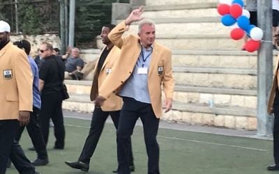 Joe Montana (middle) waves to fans at Kraft Family Stadium in Jerusalem on June 18, 2017. (Jacob Magid/Times of Israel)