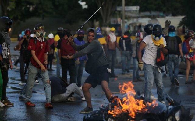 An anti-government demonstrator uses a golf club to hit a burning motorcycle protesters took from National Guards in Caracas, Venezuela, June 22, 2017. (AP/Fernando Llano) 