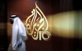 A Qatari employee of al-Jazeera TV walks past the station's logo, in Doha, Qatar, November 1, 2006. (AP Photo/Kamran Jebreili, File)