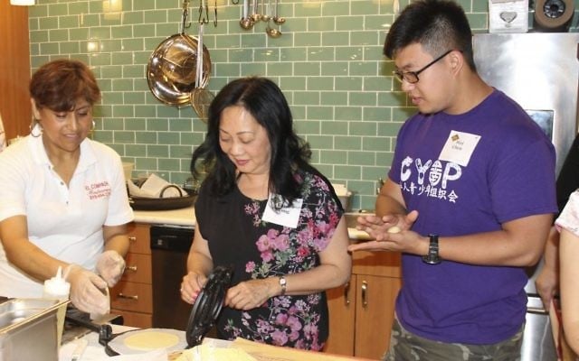 In this photo provided by Alex Styer, Cristina Martinez, left, co-owner of the Mexican restaurant El Compadre in Philadelphia, teaches Carol Wong, center, and Wei Chen, right, how to press tortillas during a June 5, 2017, dinner at Reading Terminal Market in Philadelphia. (Alex Styer/Bellevue Communications Group via AP)