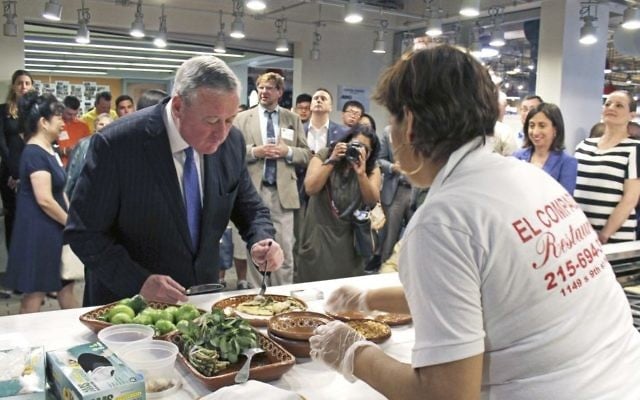 In this photo provided by Alex Styer, Philadelphia Mayor Jim Kenney, front left, samples a verdolagas con pollo dish prepared by Cristina Martinez, front right, co-owner of the Mexican restaurant El Compadre in Philadelphia, during a June 5, 2017, dinner at Reading Terminal Market in Philadelphia. (Alex Styer/Bellevue Communications Group via AP)