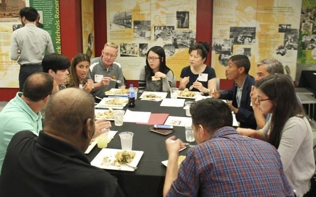 In this photo provided by Alex Styer, participants in a yearlong "Breaking Bread, Breaking Barriers" program share a meal on June 5, 2017, at Reading Terminal Market in Philadelphia. (Alex Styer/Bellevue Communications Group via AP)