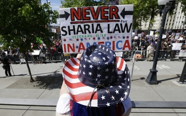 Cathy Camper, of Tacoma, Washington wears a stars-and-stripes cowboy hat as she protests against Islamic law at a rally Saturday, June 10, 2017, in Seattle, as counter-protesters demonstrate across the street. (AP Photo/Ted S. Warren) Cathy Camper, of Tacoma, Washington wears a stars-and-stripes cowboy hat as she protests against Islamic law at a rally Saturday, June 10, 2017, in Seattle, as counter-protesters demonstrate across the street. (AP Photo/Ted S. Warren)