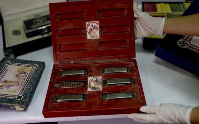 A member of the federal police shows a box with swastikas containing harmonicas for children at the Interpol headquarters in Buenos Aires, Argentina, June 16, 2017. (AP/Natacha Pisarenko) A member of the federal police shows a box with swastikas containing harmonicas for children at the Interpol headquarters in Buenos Aires, Argentina, June 16, 2017. (AP/Natacha Pisarenko)