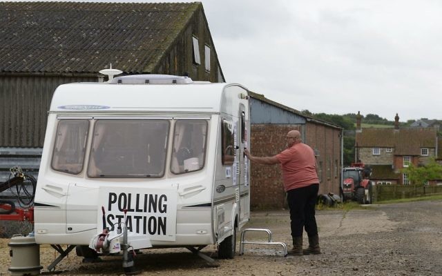 A man leaves a caravan which is being used as a polling station on Grange Farm in Garthorpe, Leicestershire, England, June 8, 2017. (Joe Giddens/PA via AP)