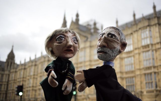 Two anti-Brexit activists pose with their hand-puppets depicting British Prime Minister and leader of the Conservative party Theresa May, left, and Britain's Labour party leader Jeremy Corbyn, during a protest, in front of the the Houses of Parliament on election day in London, Thursday, June 8, 2017. (AP Photo/Markus Schreiber)