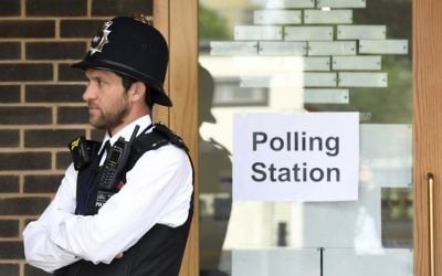 A police officer is stationed outside a polling station at Cubitt Town Infant and Junior School on the Isle of Dogs in London, as people cast their votes in the general election, Thursday June 8, 2017. (Victoria Jones/PA via AP)