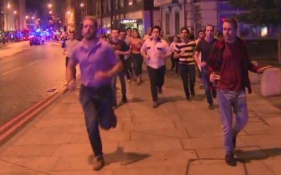 In this image taken from video footage, people run from the scene of attack, alongside a man strolling holding a pint of beer, right, in London, late Saturday, June 3, 2017. (Sky News via AP)