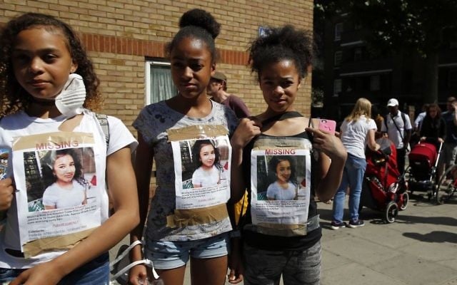 Girls have photos of a missing child on their t-shirts near scene of the massive fire in Grenfell Tower, in rear, in London, Thursday, June 15, 2017. A massive fire raced through the 24-story high-rise apartment building in west London early Wednesday. (AP/Alastair Grant) Girls have photos of a missing child on their t-shirts near scene of the massive fire in Grenfell Tower, in rear, in London, Thursday, June 15, 2017. A massive fire raced through the 24-story high-rise apartment building in west London early Wednesday. (AP/Alastair Grant)