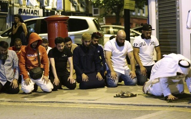 Local people observe prayers at Finsbury Park where a vehicle struck pedestrians in London Monday, June 19, 2017. Police say a vehicle struck pedestrians near a mosque in north London, leaving several casualties and one person was arrested. (Yui Mok/PA via AP) 
