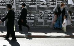 Illustrative: Ultra-Orthodox boys and a family walk past a poster that says the internet brings cancer in Jerusalem, July 2, 2009. (Rishwanth Jayapaul/Flash90)