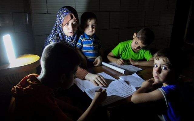 Palestinian boys study on lanterns light during a power outage in Rafah in the southern Gaza Strip on May 18, 2016. (Abed Rahim Khatib/Flash90)