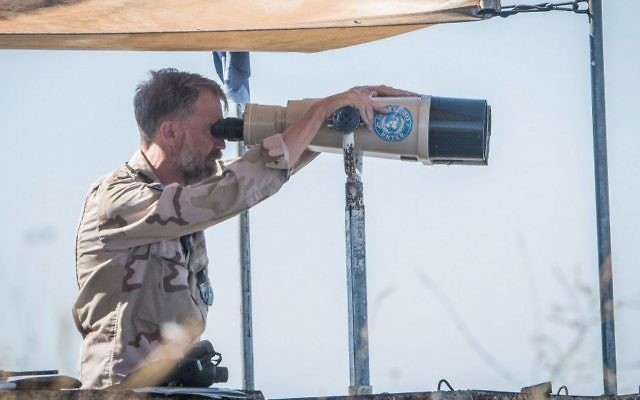 A UN observer looks through binoculars at a lookout point as smoke rises from a Syrian village near the Israeli-Syrian border in the Golan Heights on June 24, 2017. (Basel Awidat/Flash90) A UN observer looks through binoculars at a lookout point as smoke rises from a Syrian village near the Israeli-Syrian border in the Golan Heights on June 24, 2017. (Basel Awidat/Flash90)