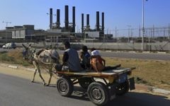 In this  June 4, 2017, photo, a father and his children ride their donkey cart past the idled Gaza power plant at Nusseirat, in the central Gaza Strip (AP Photo/Adel Hana)